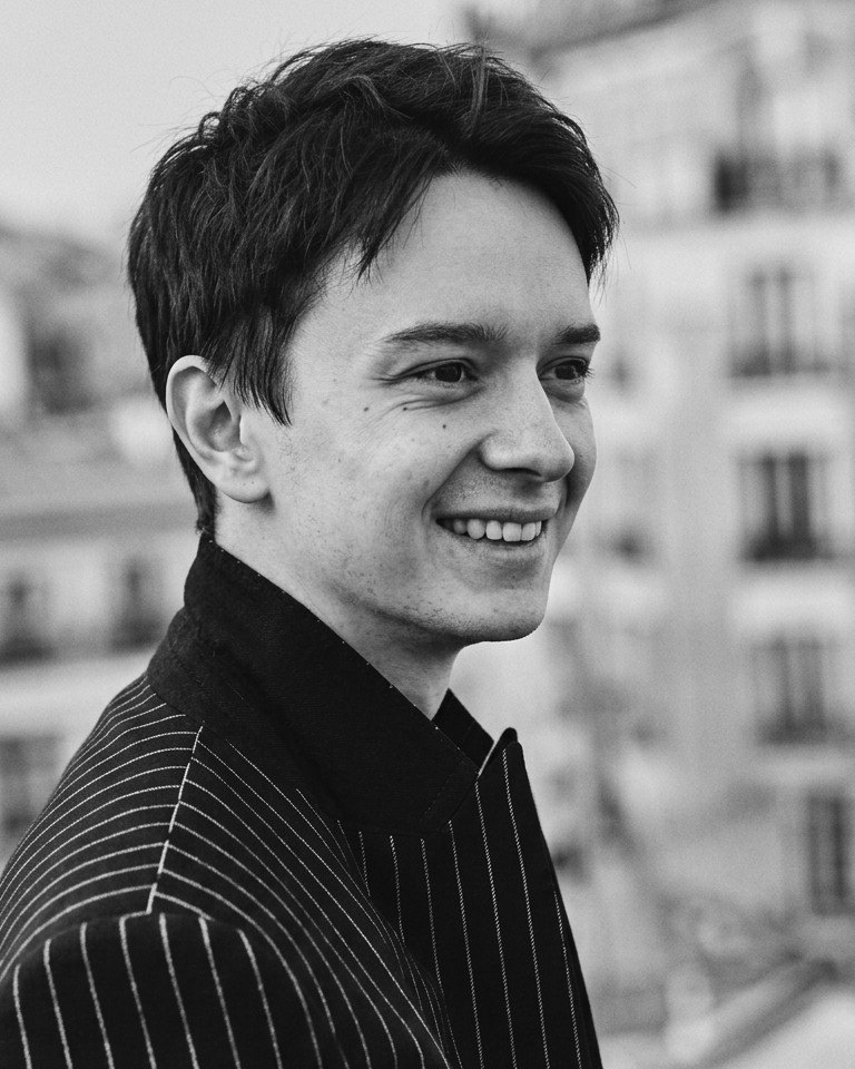 Alex Kietov smiling, in a black pinstripe jacket, black-and-white photo