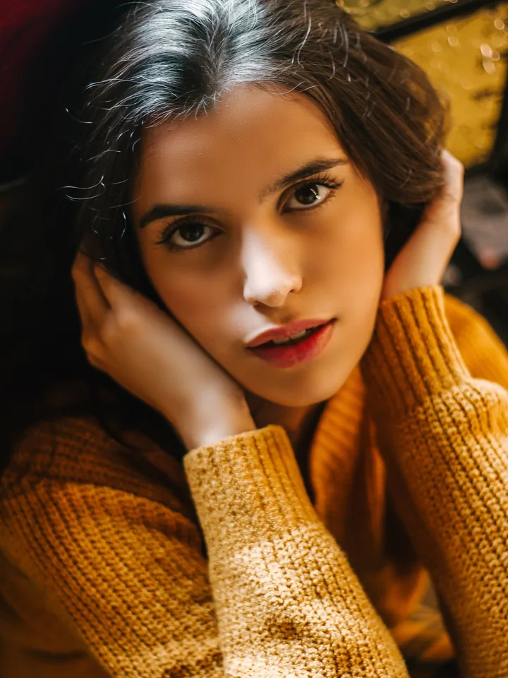Model in a mustard knit sweater with a soft brown eye and a rosy lip
