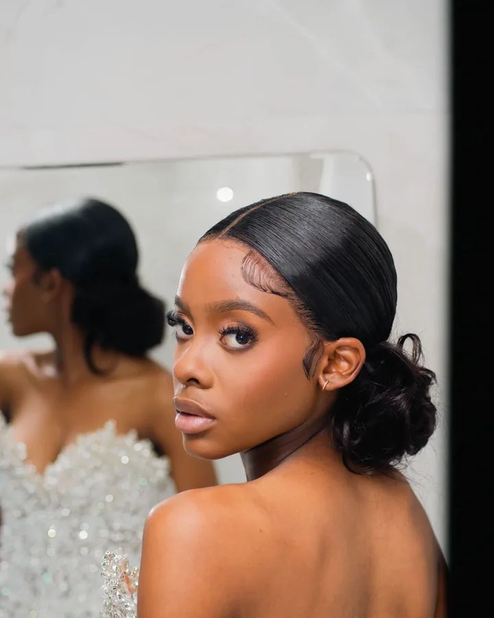 Bride with a sleek low bun and a sculpted eye looking over her shoulder in a beaded gown