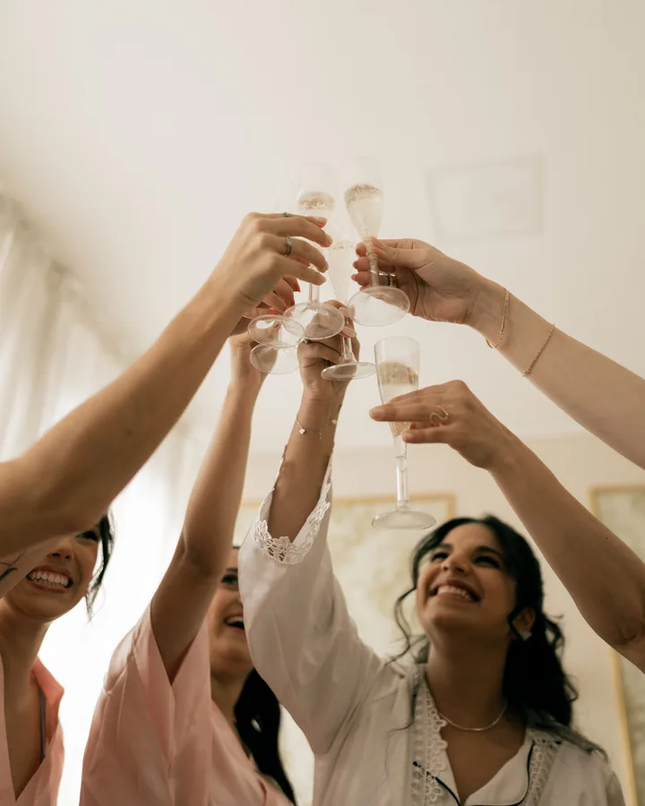 Bride and bridesmaids raising champagne glasses in a bright room