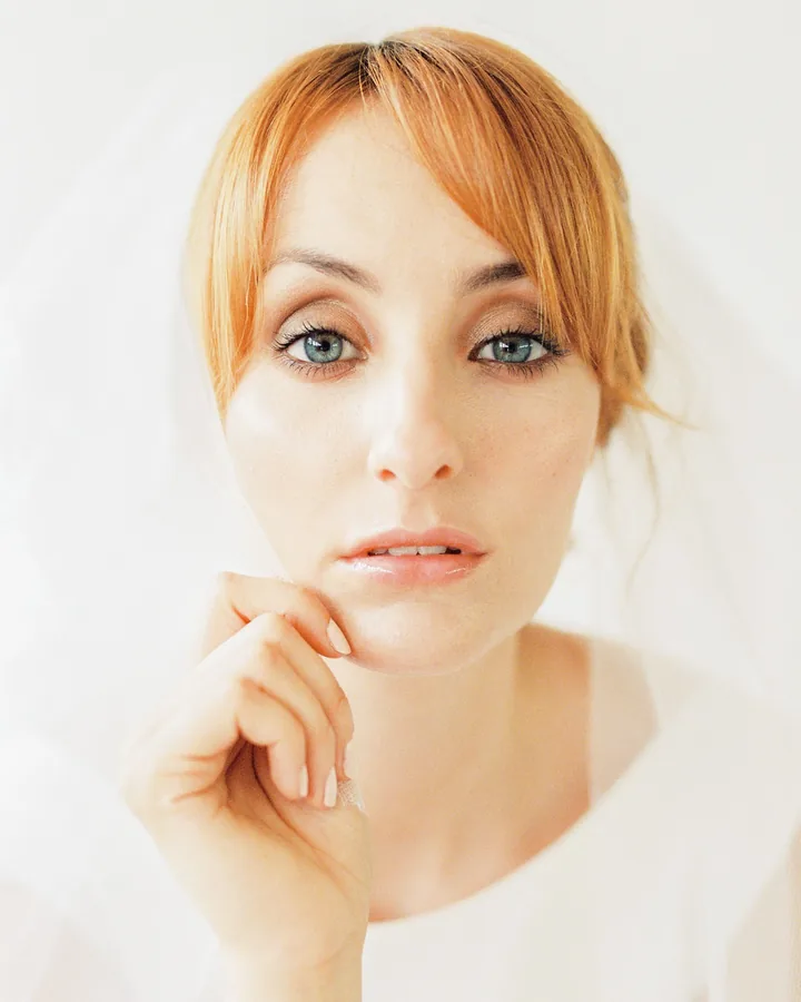 Red-haired bride under a veil with fresh, barely-there makeup