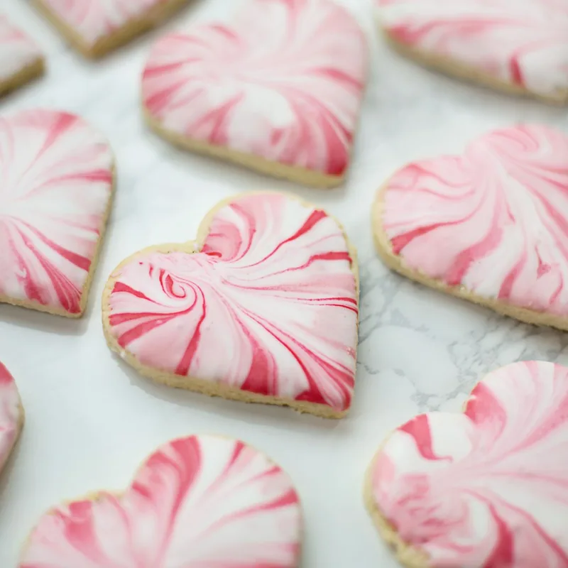 Heart-shaped sugar cookies with pink and white marbled icing
