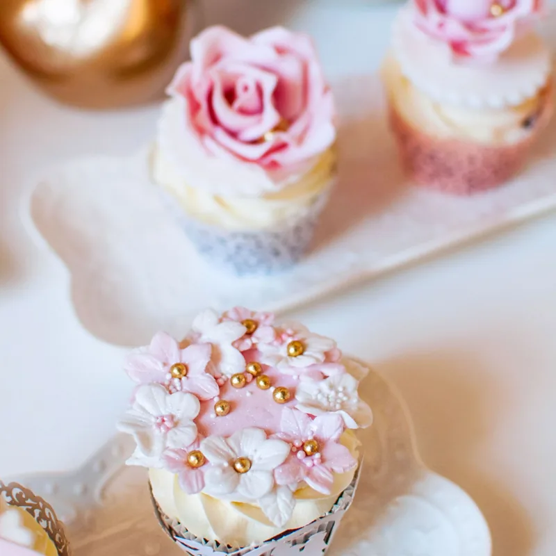 Cupcakes topped with piped pink roses and a cluster of tiny pink blossoms