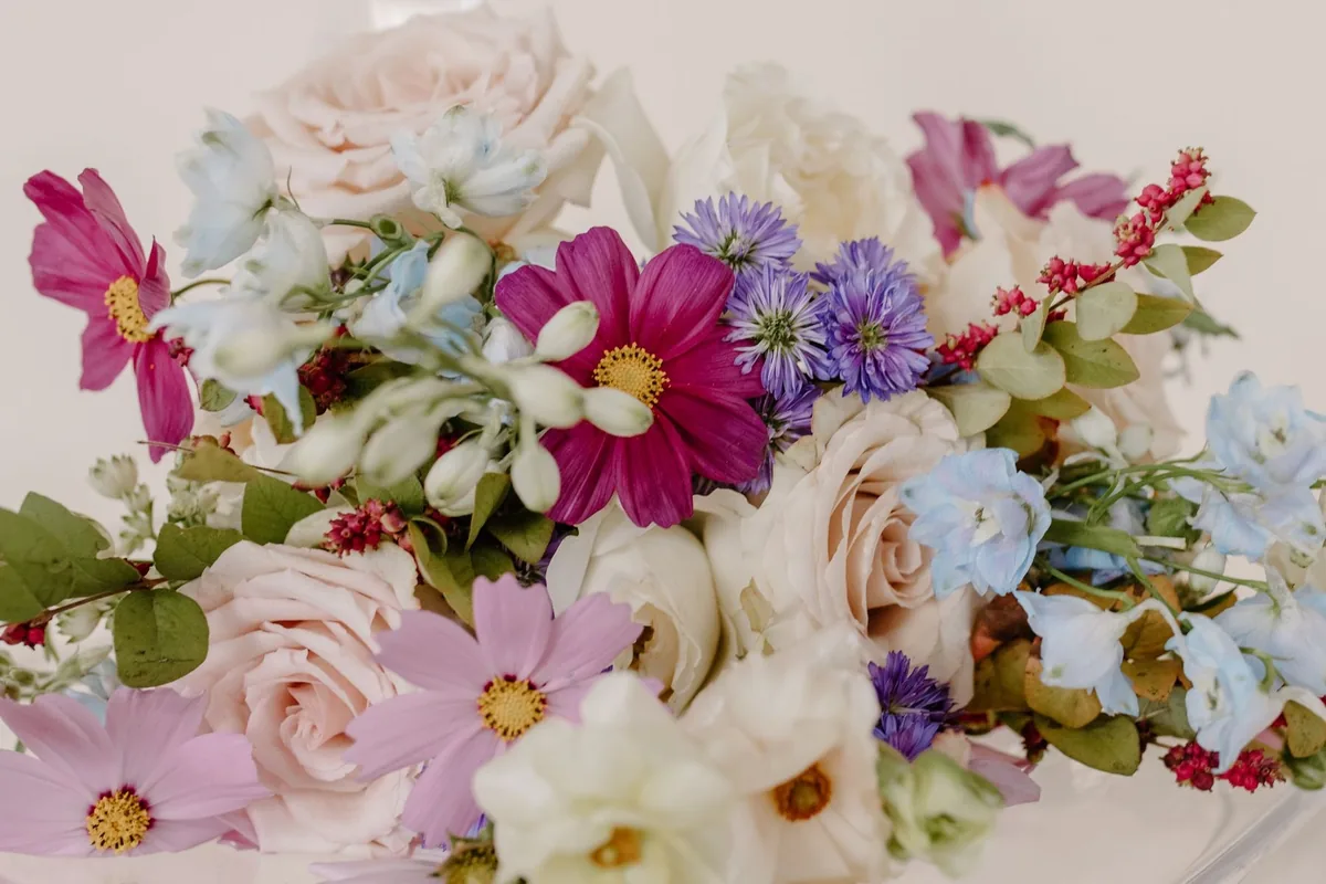 Loose arrangement of pink cosmos, blush roses, delphinium and asters