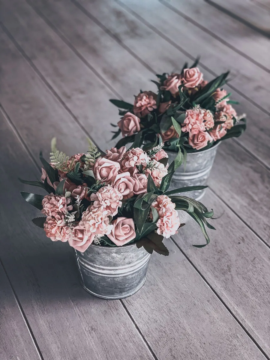 Zinc buckets of pink roses and carnations on a wooden floor, ready to load