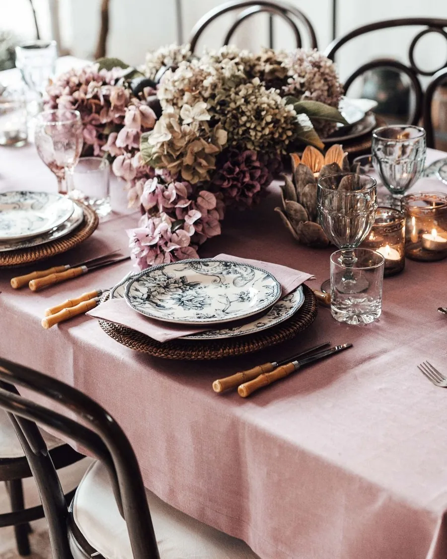 Dinner table with a mauve linen cloth, patterned plates and a low arrangement of dusty pink hydrangea