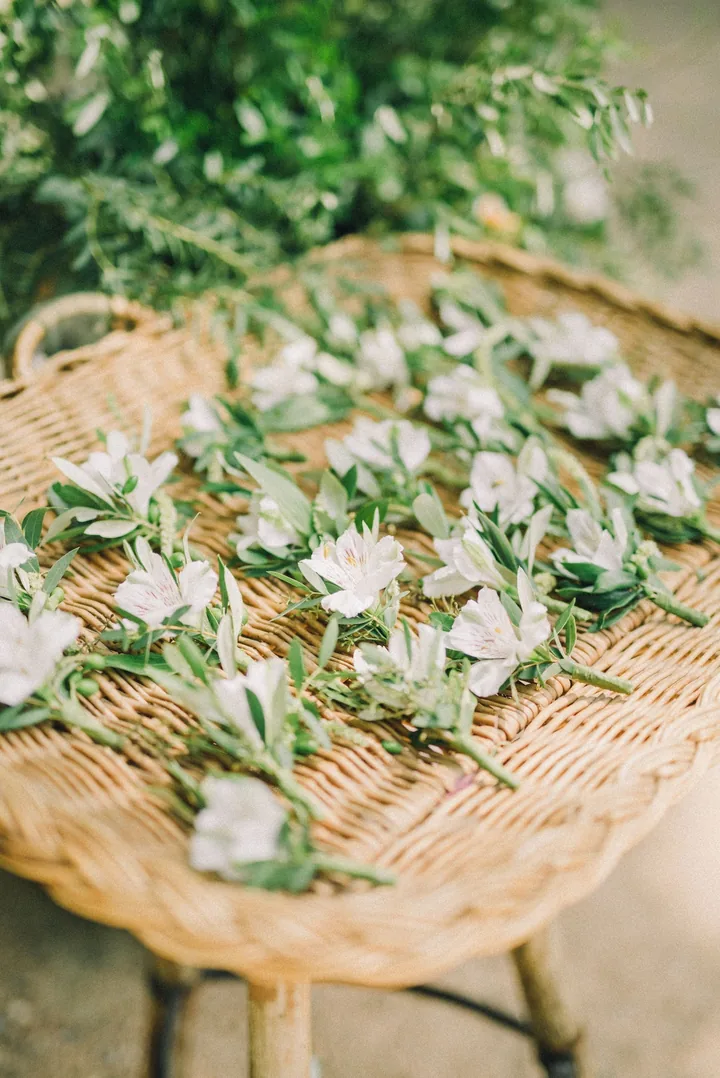 Rows of small white boutonnieres laid out on a woven basket
