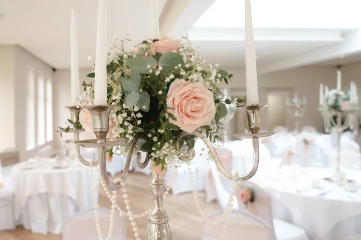 Silver candelabra with a blush rose and baby's breath arrangement in a bright reception room