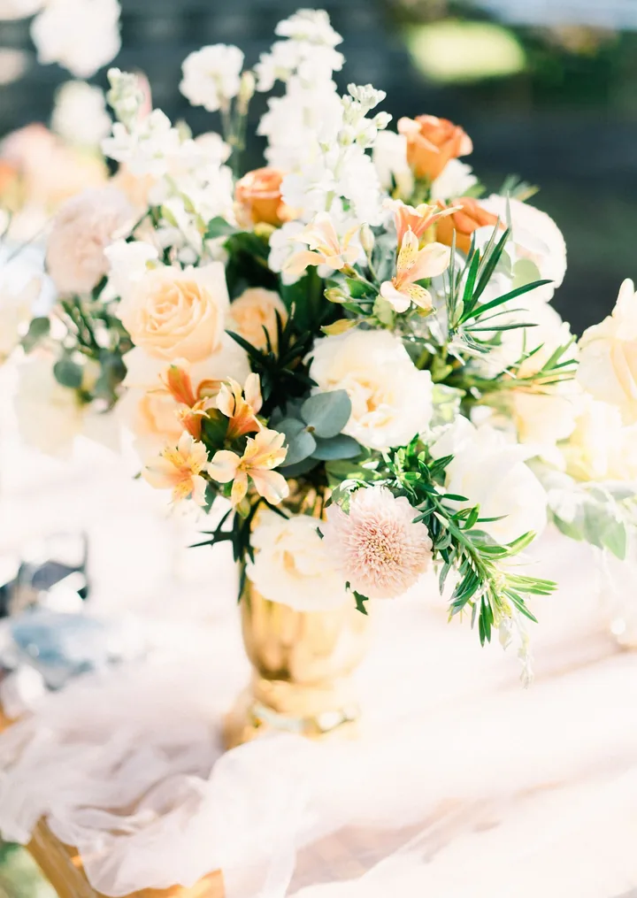 Peach and ivory arrangement with stock, roses and alstroemeria in a gold vase