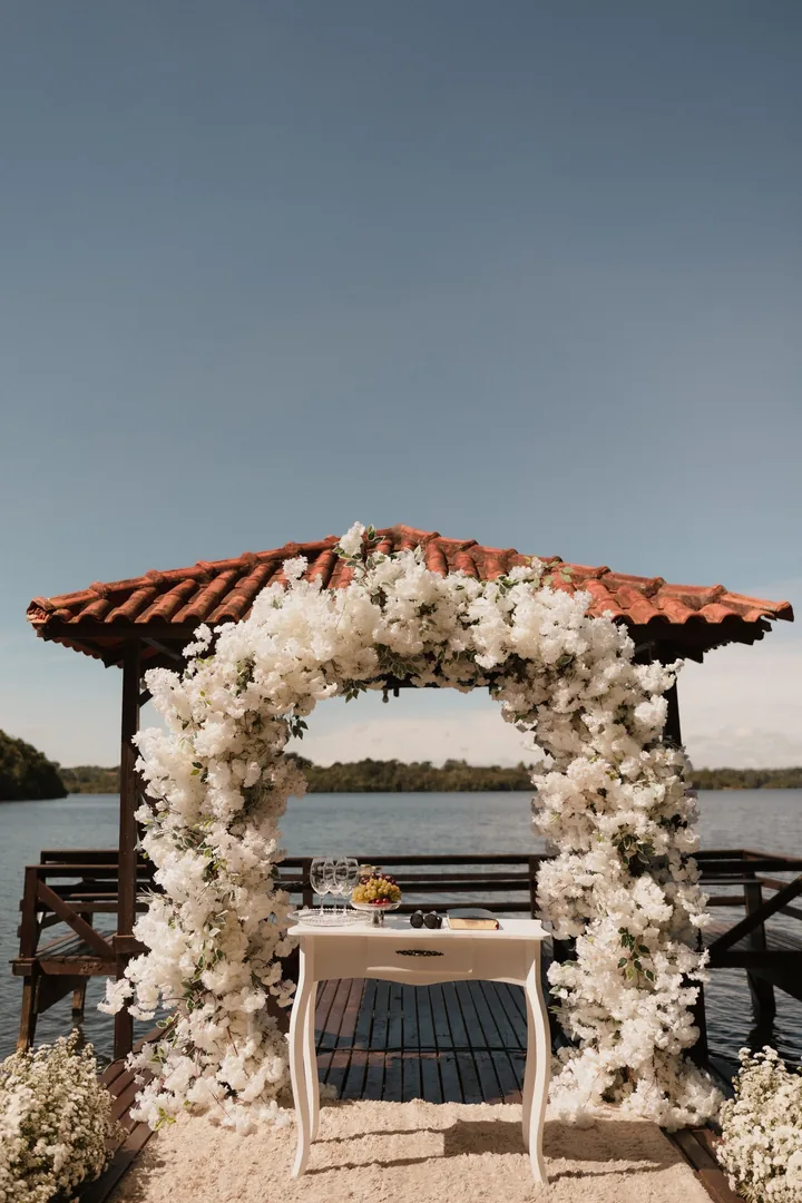 White flower arch at the end of a lakeside deck