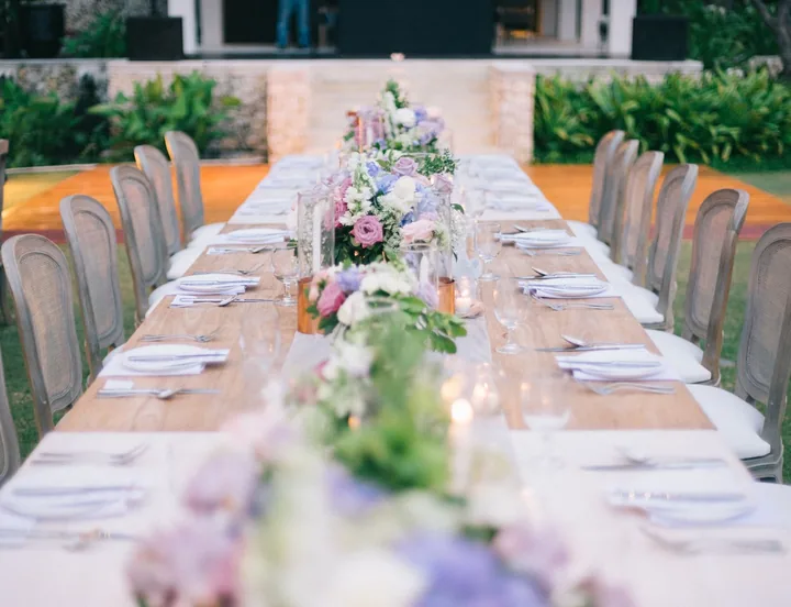 Long outdoor table with a runner of lilac, blush and white flowers
