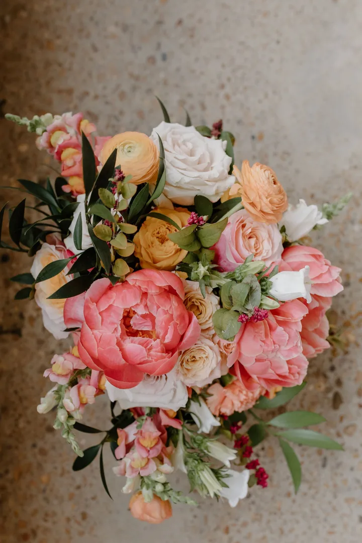 Bouquet of coral peonies, apricot ranunculus and white roses seen from above