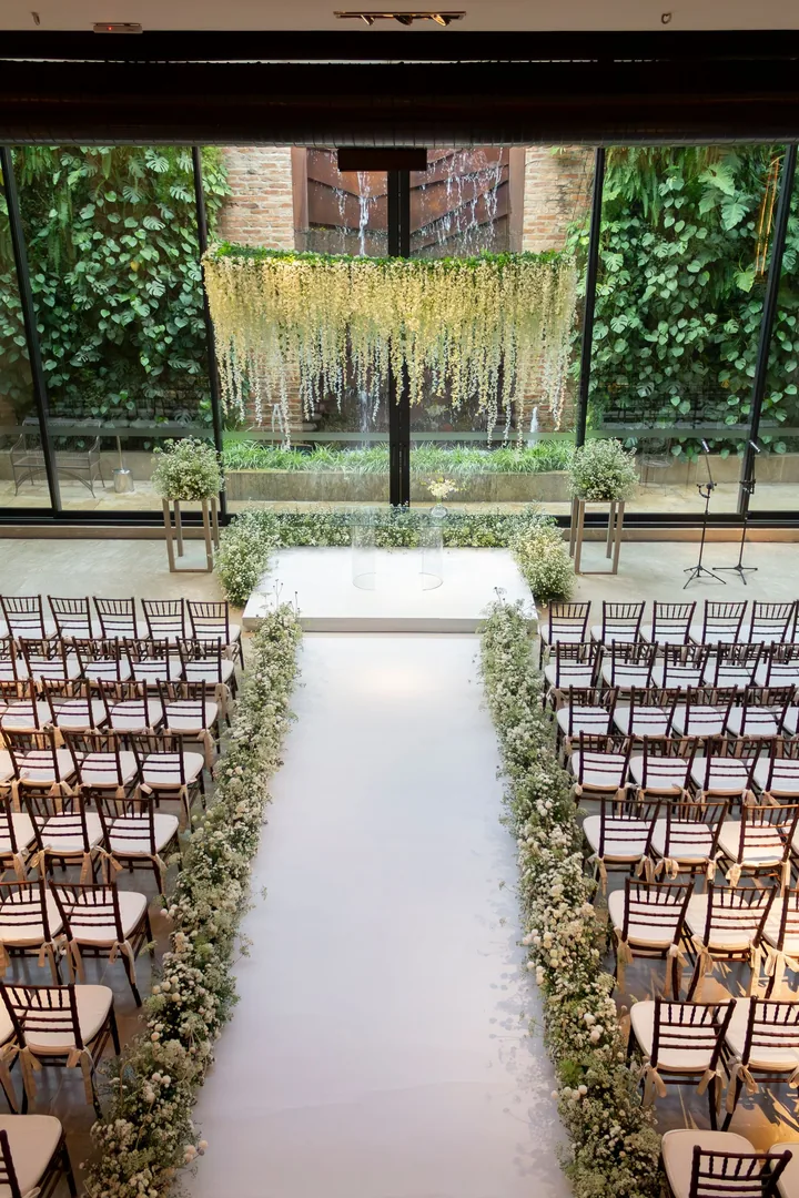 White aisle lined with baby's breath leading to a hanging curtain of white wisteria