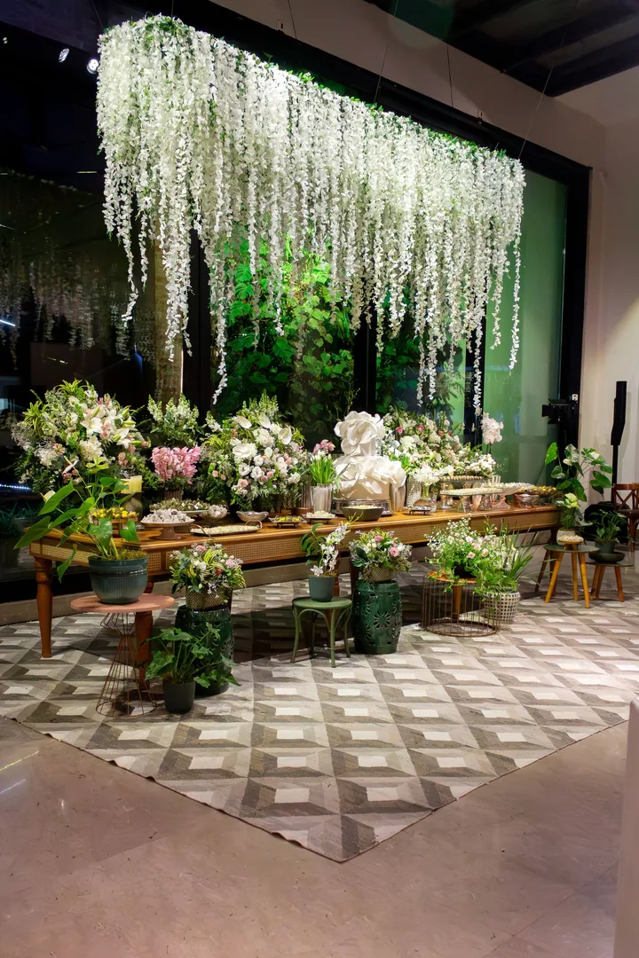 Hanging installation of white wisteria above a long table of potted flowers