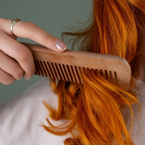 Bright copper hair combed through with a wooden comb