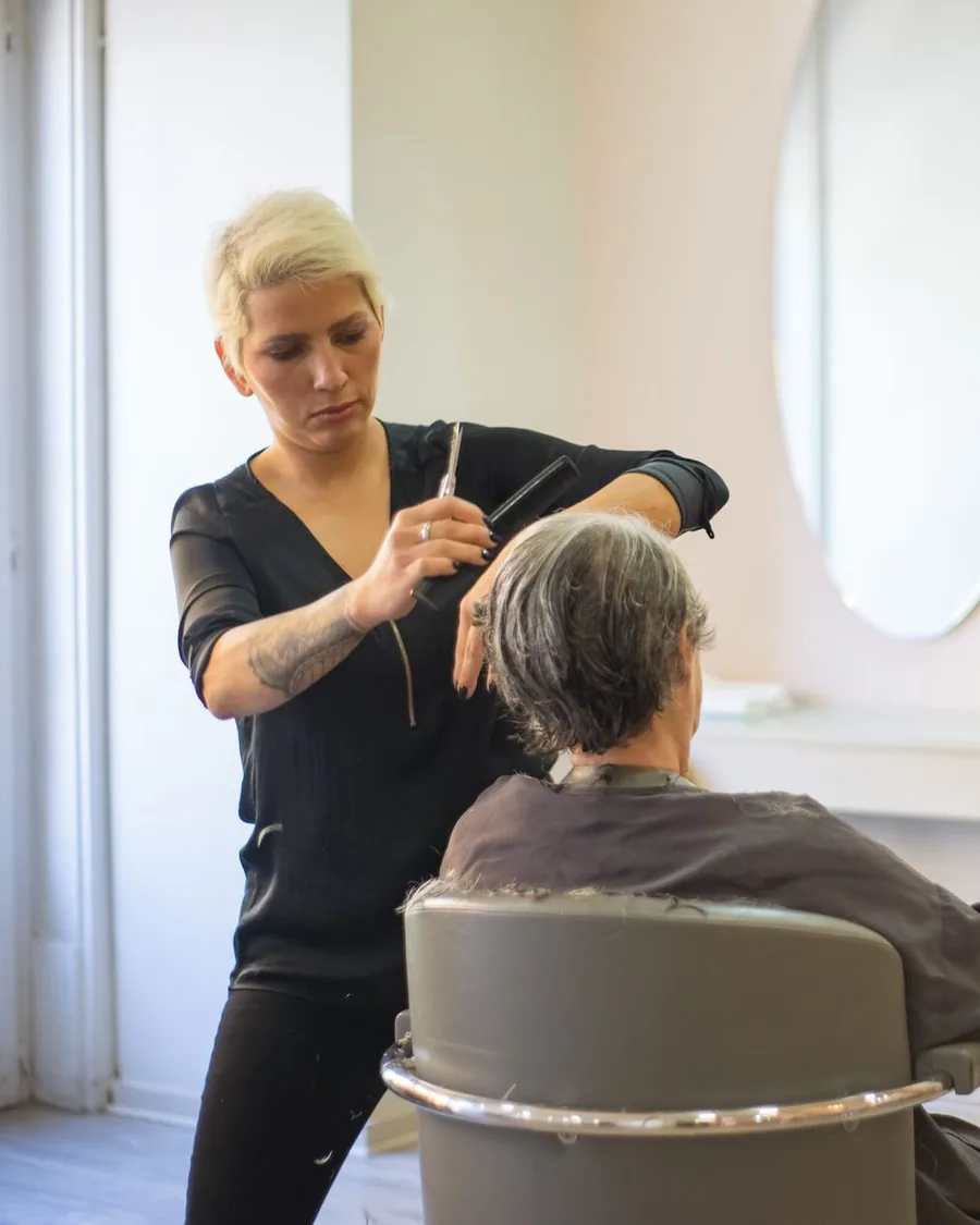 Nora cutting a client’s short grey hair in a bright room