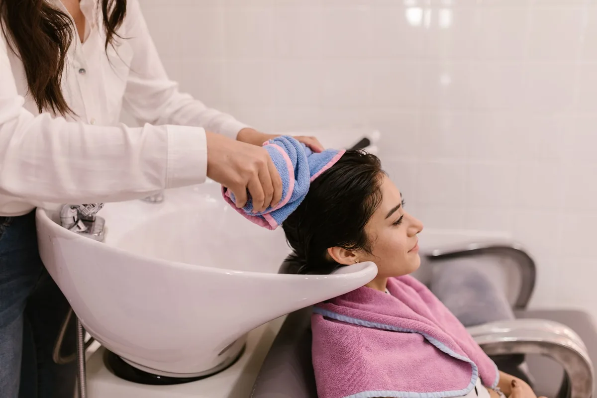 A client relaxing at the wash bowl while her hair is towel-dried