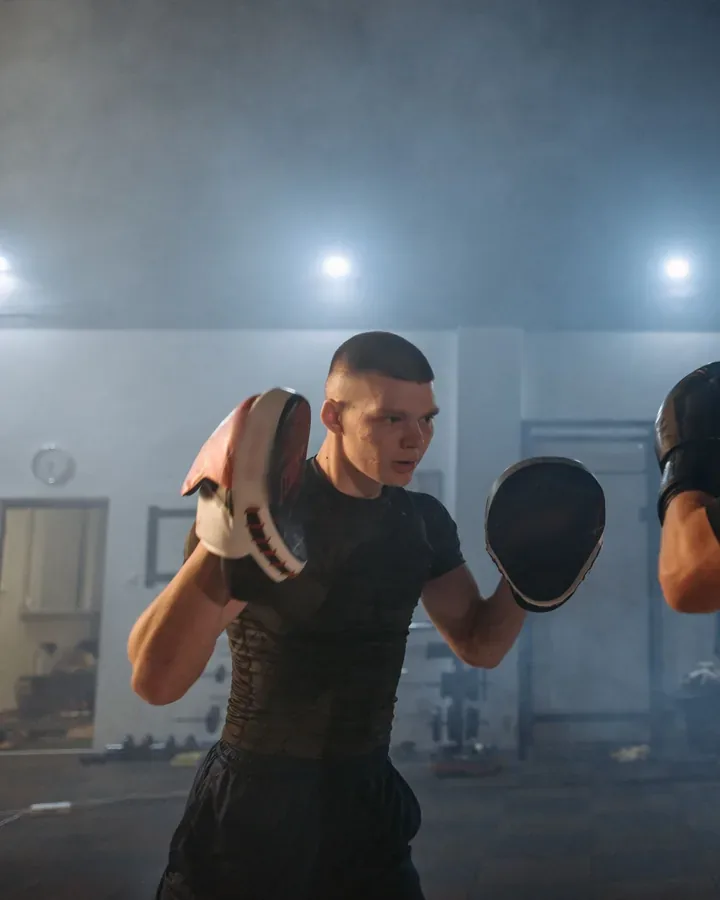 A coach holds focus mitts for a student