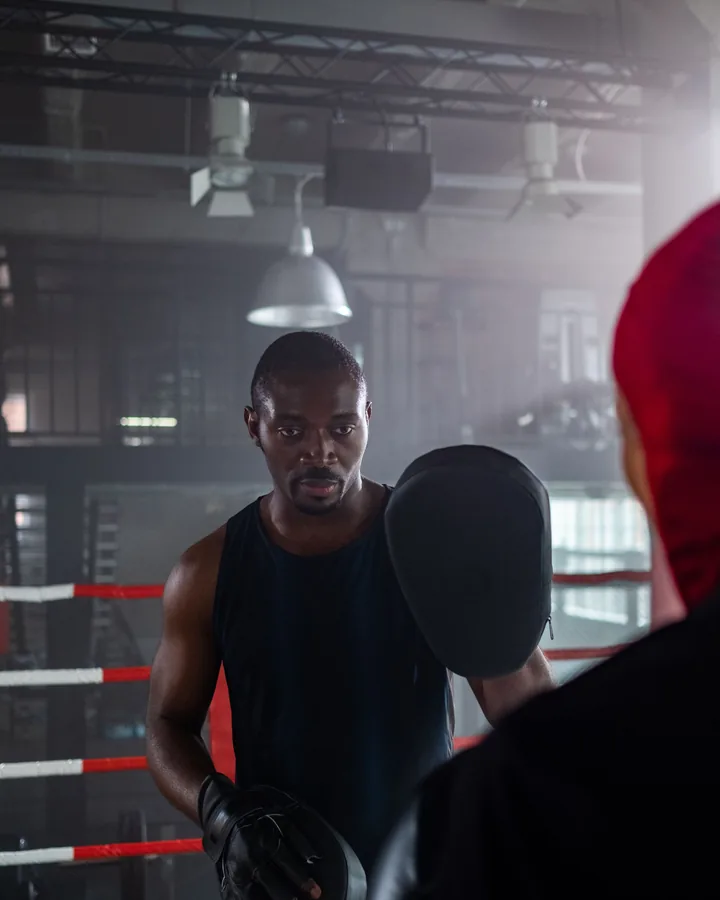 A coach holds pads in the ring