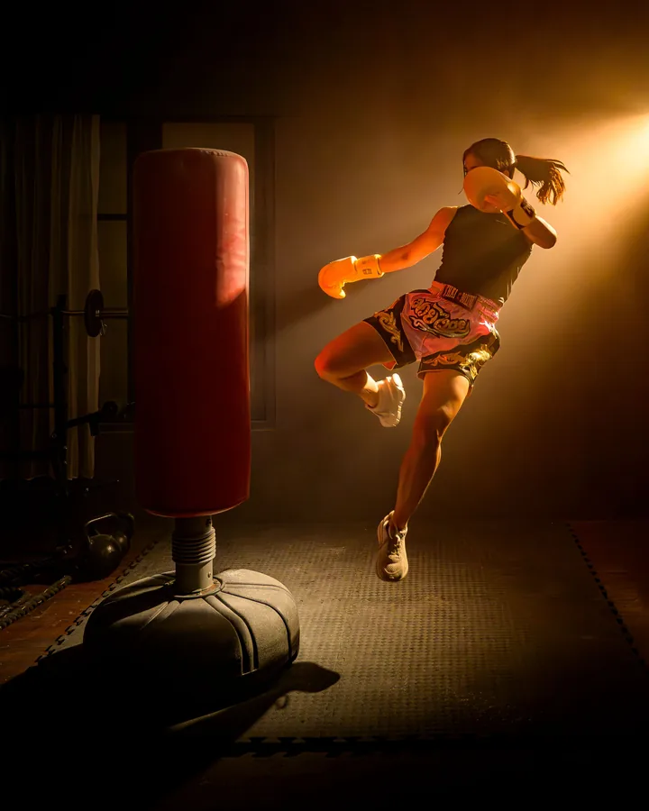 A woman throws a flying knee at a standing bag