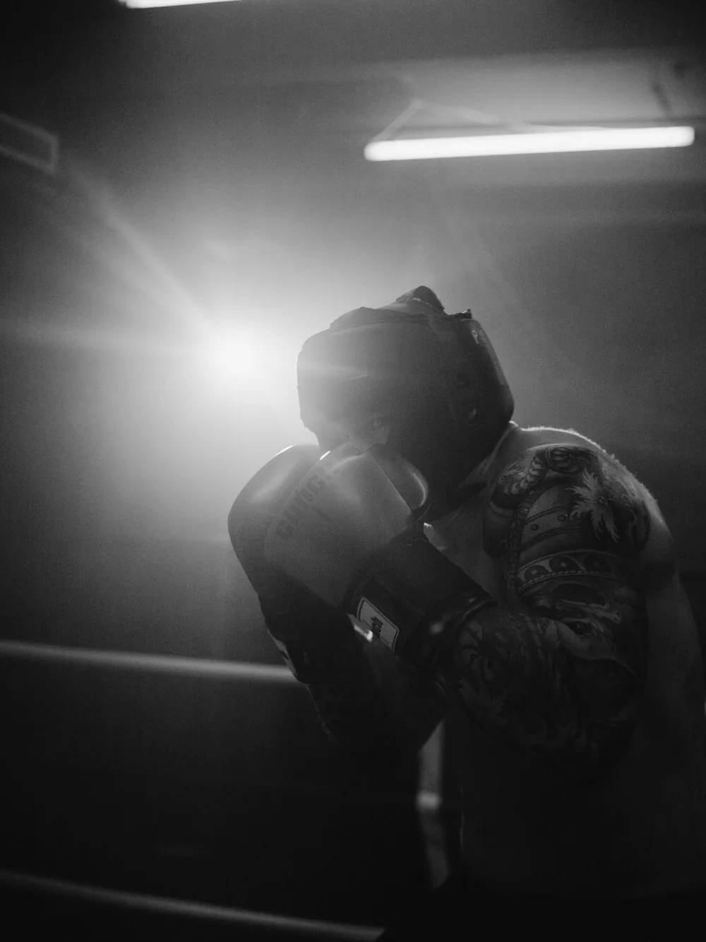 A fighter keeps a high guard in the corner, black and white