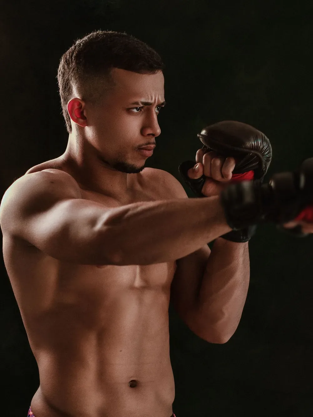 A fighter shadowboxes in the dark, eyes on his target