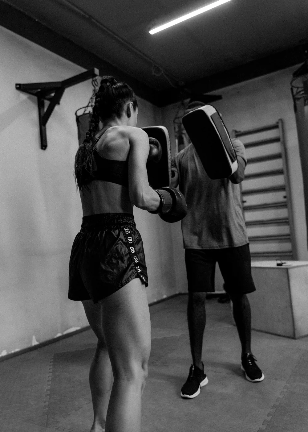 Pad work on the gym floor, black and white