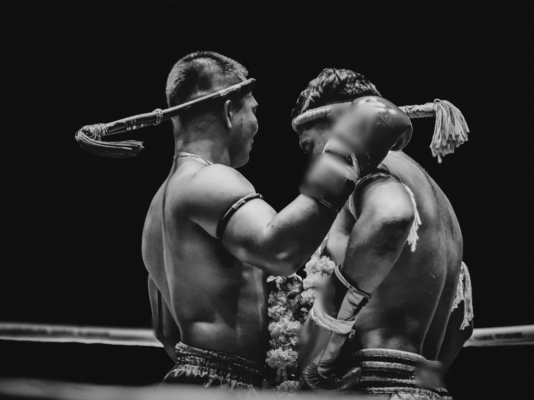 Two fighters in the clinch at a stadium in Thailand, black and white