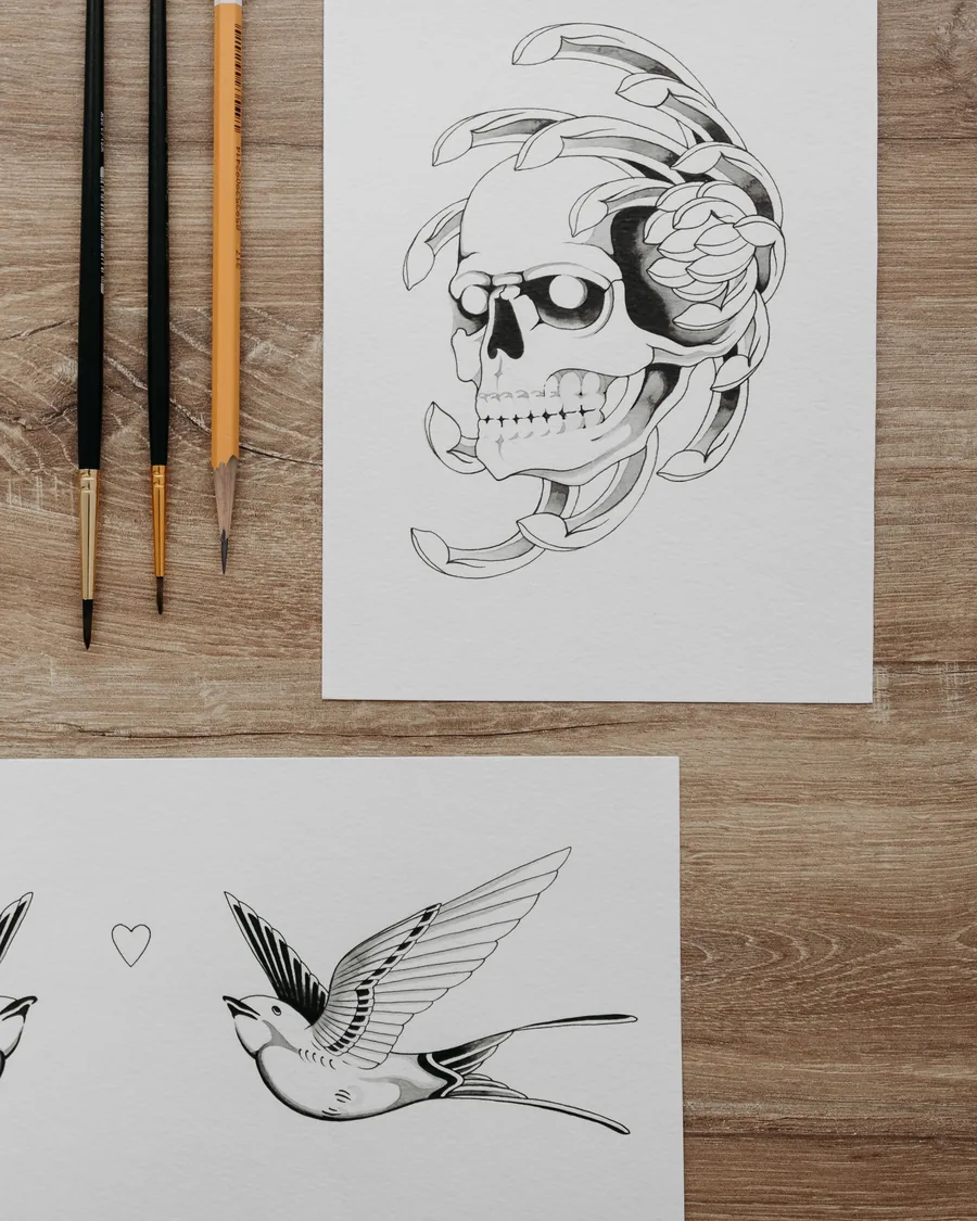 Hank's blackwork flash on paper: a skull wrapped in petals and a swallow