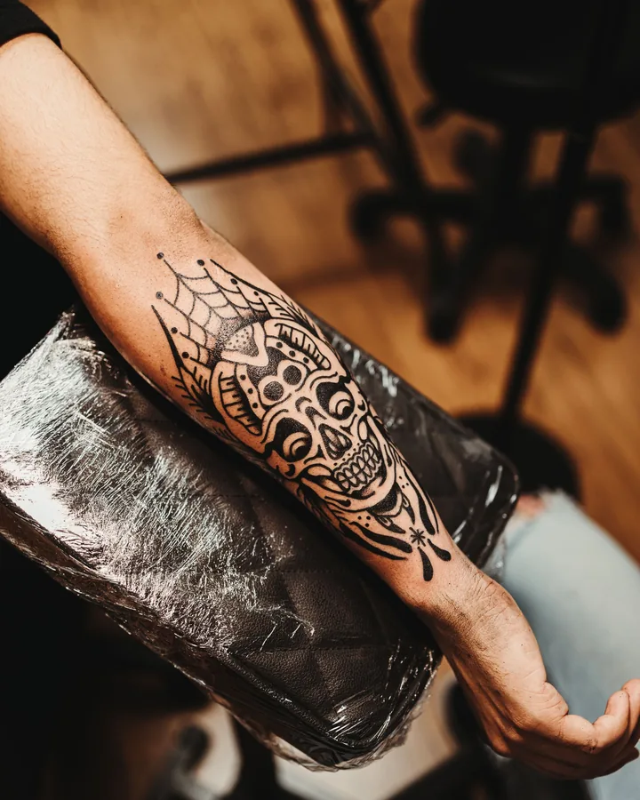 Blackwork skull and web forearm by Hank